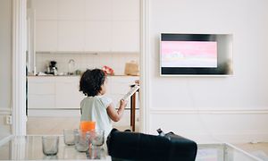 Lille pige med fjernbetjening i hånden foran TV