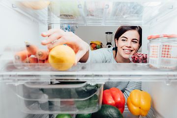 Kvinde rækker ud efter en citron i et køleskab