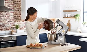 Kvinde hælder chokolade i skål, der er fastgjort til en Kenwood Chef XL Patissier køkkenmaskine