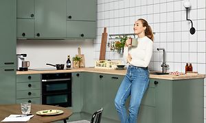 Epoq-køkken i grønt med kvinde, som læner sig op ad det