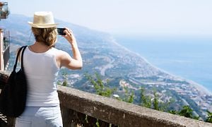 Kvinde på ferie bruger sin smartphone til at tage et billede af en kyst