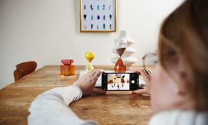 Kvinde tager et billede af genstande på et bord med sin iPhone