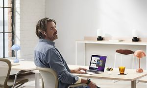 En mand, der sidder ved skrivebordet med sin MacBook