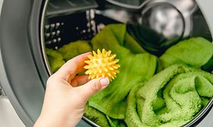 MDA-Tumble dryer- Hand putting yellow dryer ball in a dryer
