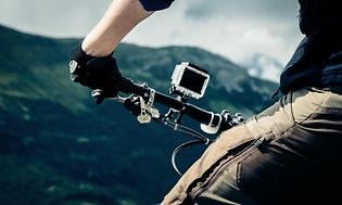 Mand ser på en bjergudsigt, og han har et actionkamera monteret på sin cykel