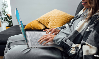 Lenovo Yoga Slim 7 Carbon - Kvinde med laptop på skødeti en sofa