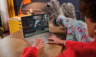 Lenovo Yoga Slim 9 - Kvinde redigerer video med benene på bordet