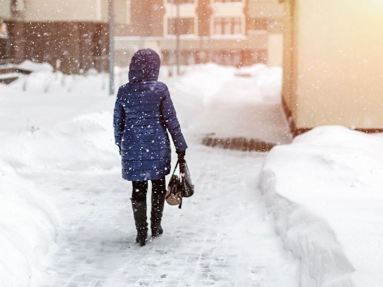 Kvinde ses bagfra på gade i snevejr