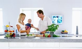 En familie i et køkken med et lille tv på væggen