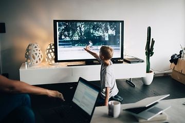En lille dreng peger på skærmen på et tv