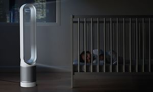 En Dyson Pure Cool Tower luftrenser ved siden af en børneseng, hvor en lille dreng sover