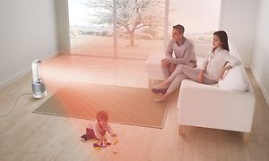 En Pure Cool Tower PP00 fordeler røde varmestråler mod en familie, der sidder på en sofa og et barn på gulvet