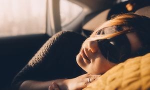 En kvinde sover i en bil med en sovemaske