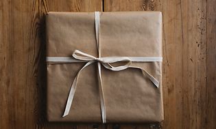En gave pakket ind i brunt papir på et træbord