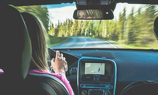 En kvinde, der kører bil med GPS-navigationen sat til