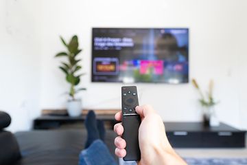 TV og opdateringshastighed: En hånd med fjernbetjening rettet mod TV