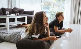 TV og opdateringshastighed: To teenagere ligger på gulvet og ser TV
