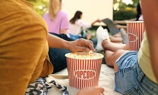 Et par spiser popcorn og ser på en skærm udenfor