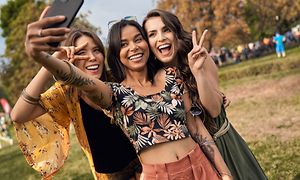 Tre piger tager et billede med en smartphone