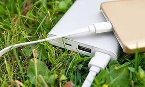 Powerbank oplader en smartphone i græsset