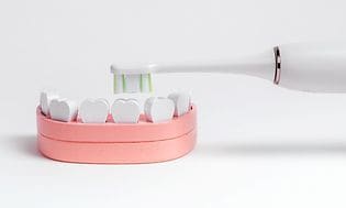 Plastiktænder, der illustrerer et barns mund og en elektrisk tandbørste