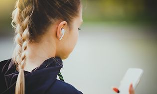 Trådløse høretelefoner i ørerne på kvinde, der tjekker sin mobil