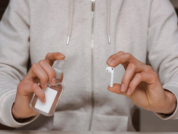 Vedligehold af trådløse høretelefoner: Person gør klar til at rengøre AirPods