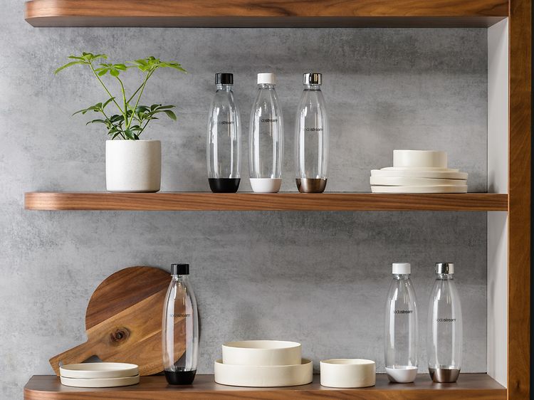 Seks Sodastream-flasker i forskellige størrelser på flere hylder