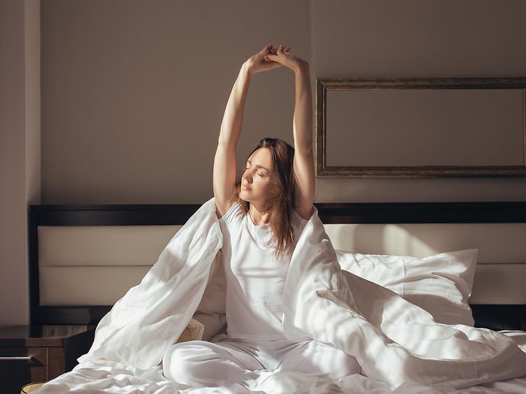 Få din gode døgnrytme tilbage: Ung kvinde strækker sig i sin seng