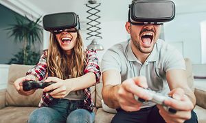Mand og kvinde spiller videospil med virtual reality-briller på