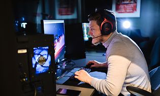 Mand, der spiller på gaming-PC, og som har et HyperX gaming-headset på hovedet
