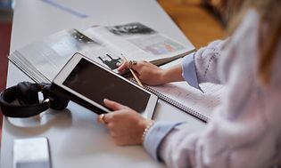Studerende med tablet og bøger samt notesblok