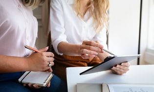 To forretningskvinder sammenligner noter på hver sin tablet