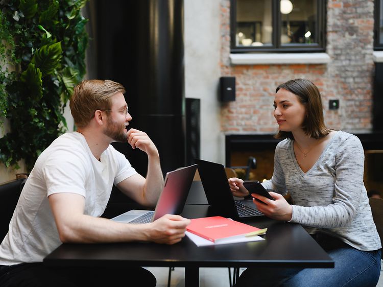 Mand og kvinde arbejder sammen på hver deres laptop
