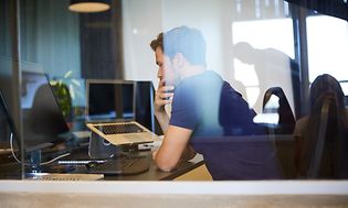 Mand sidder ved et skrivebord og arbejder på et kontor