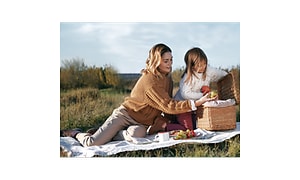 A woman and a child sitting outside having a picnic