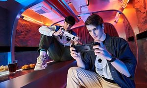 To unge mænd gamer på deres ROG Phone 6 i et farverigt rum med stenvægge