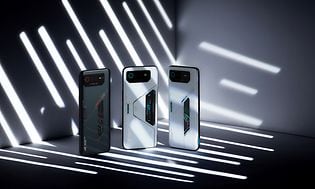 Typerne af ROG Phone 6-serien, der står i et mørkt rum med striber af lys, der skinner på dem