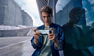 En ung mand med hvid ROG Phone 6 udenfor i regnen
