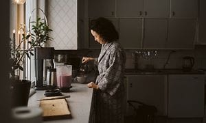 Kvinde i et køkken med blender med smoothie ved siden af hende