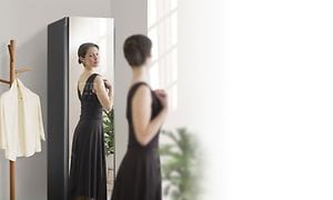 Woman stading in front of the mirror on her LG Styler looking at herself in a black dress
