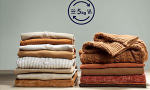 Two piles of folded laundry with a Electrolux symbol for Ultra Wash and Dry above it