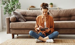 Kvinde sidder på gulvet og bruger en tablet