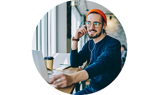 Man in cafe wearing headphones looking at laptop