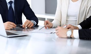 Forretningsfolk diskuterer kontrakt ved møde siddende omkring et skrivebord