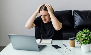 En frustreret mand foran sin bærbare computer