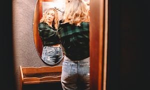 Kvinde bruger krøllejern mens hun kigger sig i spejlet