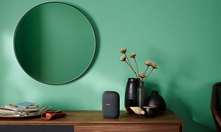 Charcoal Google Nest Audio standing on a sideboard in what looks like a hallway