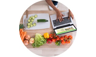 Laptop på et bord med grøntsager
