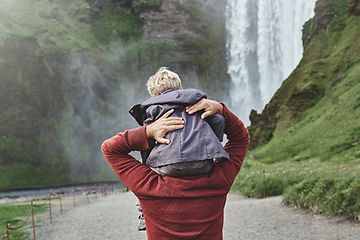 Far med søn på skuldrene ved et vandfald